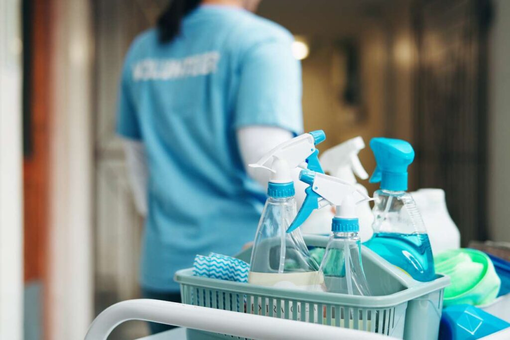 Cleaner walking through hallway with cleaning supplies